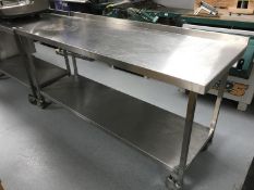 A stainless steel two tier preparation table, on wheels,