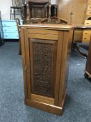 A satin walnut pot cupboard with a carved panel door