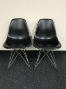 A pair of Vitra Eames black plastic chairs on chrome legs,