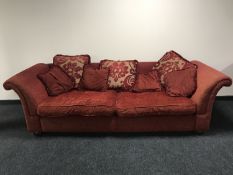 A three seater settee and a two seater scroll arm settee in a red fabric with scatter cushions