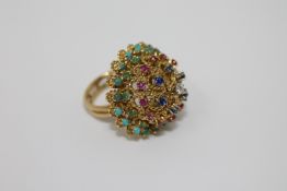 A high carat gold multi-gemstone ring, set with tiers of turquoise, emeralds, rubies,