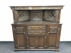 A carved oak buffet back sideboard with leaded glass doors