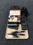 A tray consisting of cased binoculars, cameras, two miniature knives in the form of samurai swords,