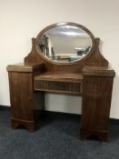 An early 20th century mahogany kneehole dressing table with pillar cabinet supports and an oval