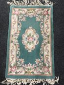 Three fringed Chinese rugs on green ground