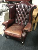 A red button leather Chesterfield style wingback armchair