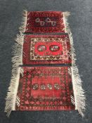 Three Persian fringed woollen rugs on red ground