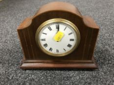 An inlaid mahogany mantle clock on brass feet
