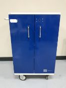 A double sided metal medical cabinet on wheels with keys
