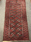 A fringed Afghan rug on red ground,