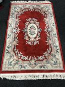 A fringed Chinese rug on red ground