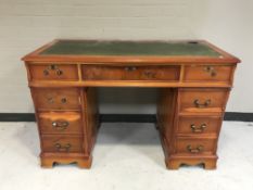 A yew wood writing desk fitted nine drawers with inset green leather panel