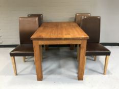 A contemporary dining table and four brown leather chairs