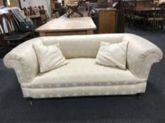 A late Victorian settee upholstered in a cream fabric