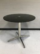 A glass topped table on a chrome pedestal