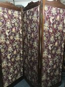 A pine three way folding room divider upholstered in a burgundy floral fabric