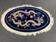 A oval fringed Chinese rug with dragon design on a blue ground