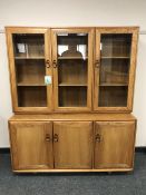 An Ercol light elm glazed triple door bookcase with cupboard base,