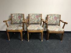 A set of three teak framed armchairs upholstered in a floral fabric