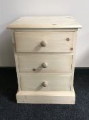 An unfinished pine three drawer bedside chest