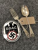 A fork and spoon bearing swastika emblem and two reproduction German badges