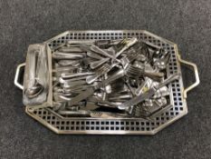 A metal twin handled serving tray and a large quantity of stainless steel cutlery