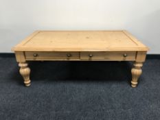 A rectangular coffee table fitted two drawers on reeded legs in a pine finish,