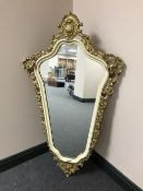 A shaped ornate cream and gilt mirror