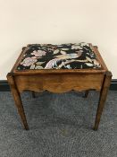 A mahogany storage piano stool containing sheet music