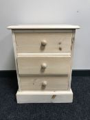 An unfinished pine three drawer bedside chest