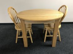 A circular contemporary kitchen extending dining table together with two chairs