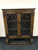 A carved oak double door bookcase with leaded glass doors