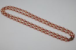 A double strand of fresh water cultured pearl and coral necklace with gilt metal clasp