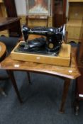 A shaped oak occasional table on reeded legs together with a Singer sewing machine