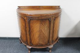 A mahogany D shaped cabinet on claw and ball feet