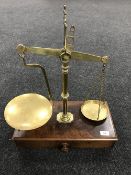 A set of Victorian brass balance scales on mahogany base fitted a drawer with weights by Barlett of