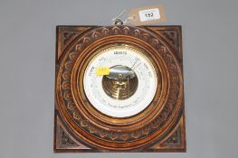 An aneroid barometer in a carved oak frame