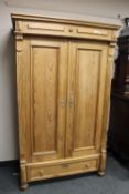 A pine double door wardrobe fitted with a drawer,