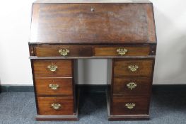 A late Victorian mahogany writing bureau on three drawer pedestals