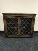 A carved oak double door bookcase with leaded glass doors