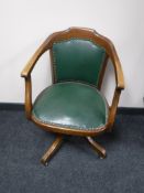 A mahogany swivel office armchair upholstered in a green button leather