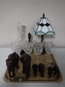 A tray containing six carved hardwood elephants, decanter, wine glasses, brass hand-bell,