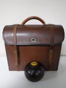 A leather bowls bag containing four vintage wooden lawn bowls