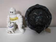 A cast metal lion mask door knocker together with a cast metal Michelin man