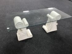 A glass topped coffee table on stone pedestals