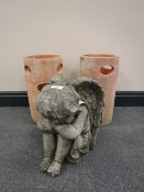 A garden figure of a resting angel and two strawberry pots