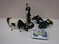Two Poole dolphins, a continental figure, china figure of a fresian cow,