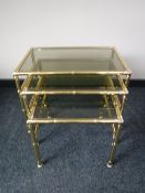 A nest of three brass glass topped tables