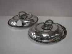 A pair of plated entree dishes with covers