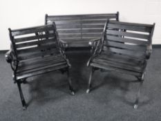 A wrought iron and wood garden bench with a matching pair of chairs